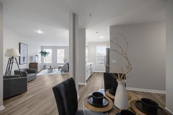 A modern living room with a black chair and a white vase on a woven tray.
